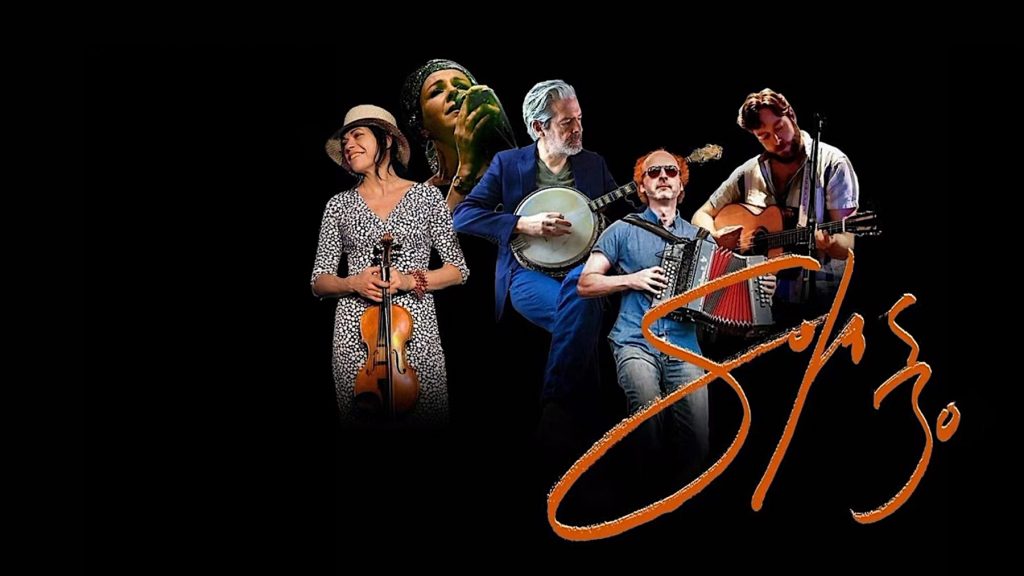 Five musicians play different instruments including violin, banjo, accordion, and guitar, with a painted orange "Solas 30" logo across the image. The background is black, highlighting the performers.
